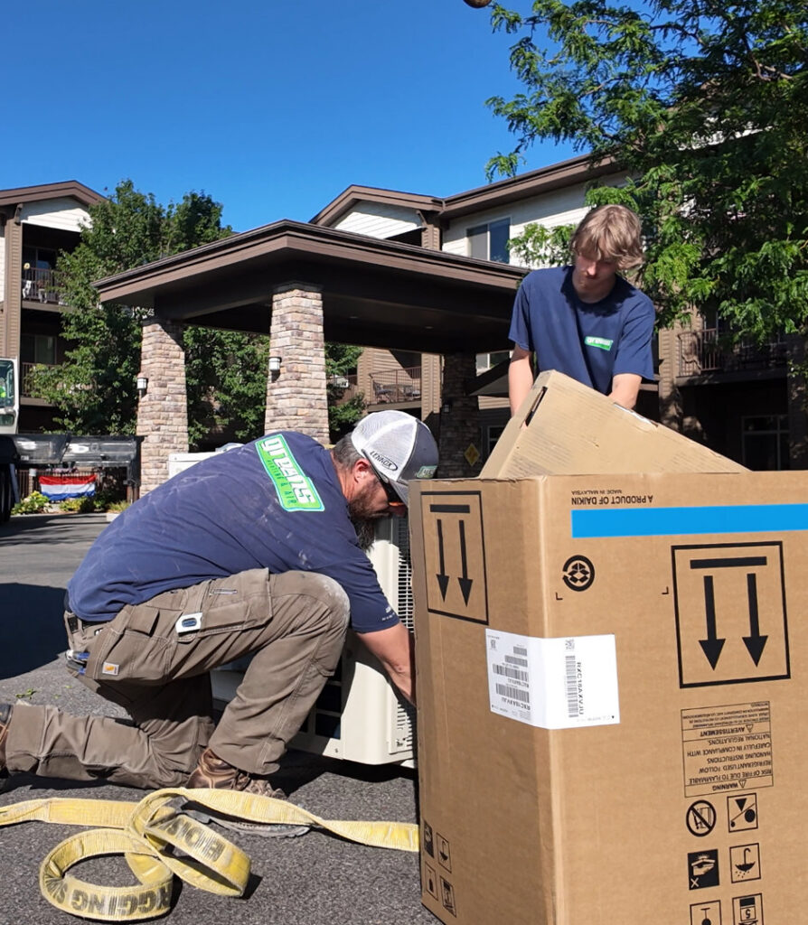 Two HVAC technicians from Greens Heating & Air Conditioning installing a new outdoor AC unit in Douglasville, GA.