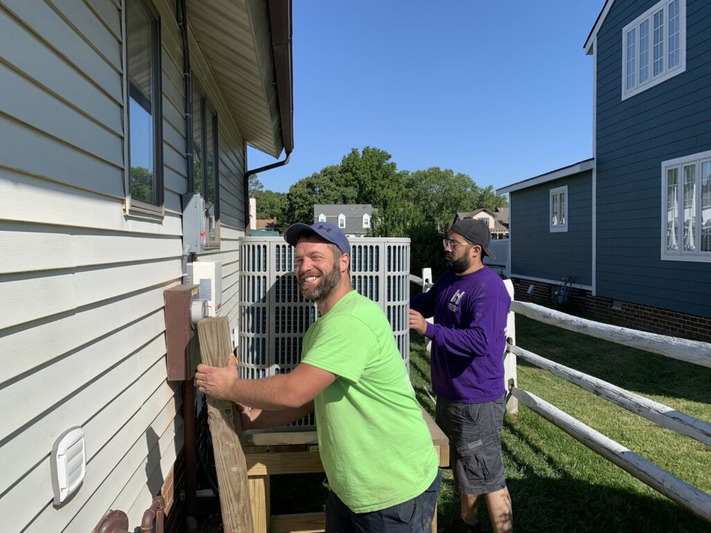 Hendrix Heating & Air technicians installing or servicing an outdoor air conditioning unit in Newport News, VA.
