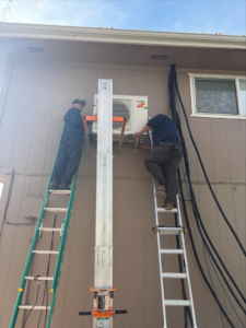 HVAC technicians installing an outdoor mini-split unit on a residential building for Royal Heating & Air LLC in Sparks, NV