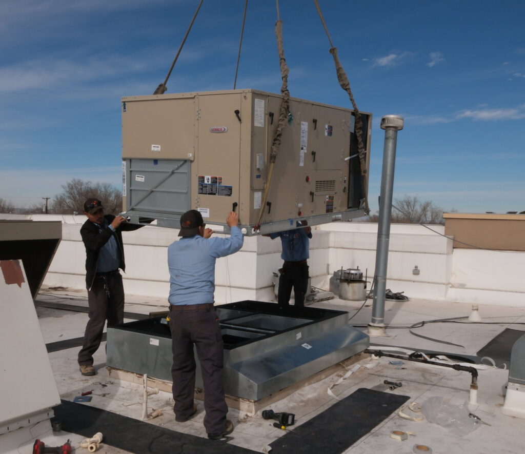 HVAC technicians installing a large commercial rooftop unit with a crane for Number 1 Plumber in Washington, DC.