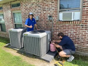 Two HVAC technicians installing or servicing outdoor AC units at a residential property for Moreau's Heating & AC in Lake Charles, LA.