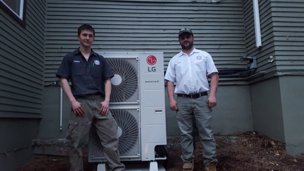 Two Semenik Hvac/r technicians standing proudly next to a newly installed LG outdoor heat pump in Spokane, WA.