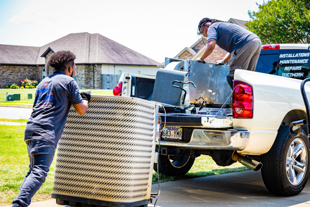 HVAC technicians from Cool Guys Heating & Air LLC loading an old AC unit onto a truck in North Little Rock, AR.