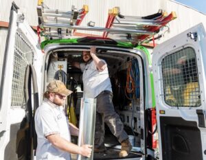 Two HVAC technicians from DFH Company Heating and Air Conditioning loading equipment into a service van in Louisville, KY.