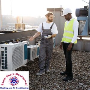 Two HVAC technicians discussing work on a commercial rooftop with multiple units for South Shore Mechanical in Abington, MA