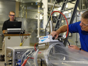 Two HVAC technicians performing duct sealing with an AeroSeal system for Garden City Plumbing & Heating in Missoula, MT