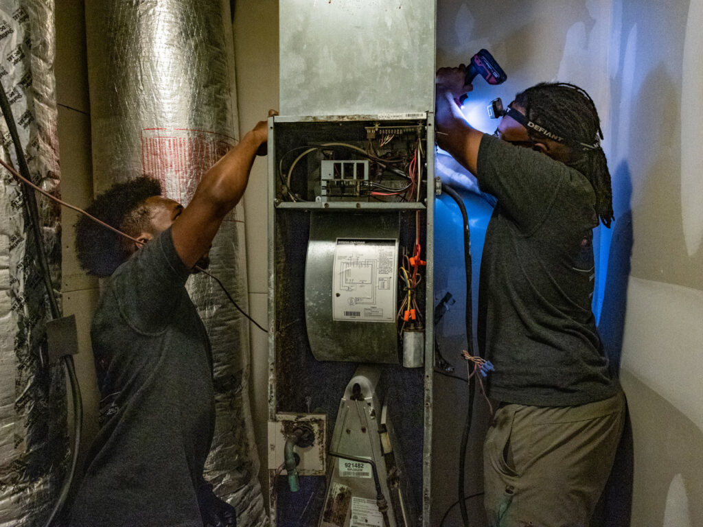 Two HVAC technicians from Cool Guys Heating & Air LLC repairing an indoor furnace in North Little Rock, AR.