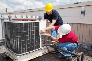 Two HVAC technicians repairing a commercial rooftop air conditioning unit for 5 Star Charleston Heating and Air in Charleston, SC.