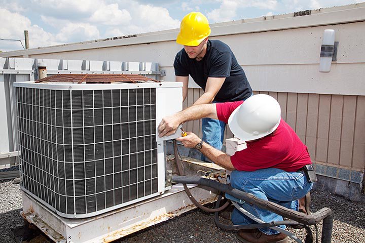 Two HVAC technicians repairing a commercial rooftop air conditioning unit for 5 Star Charleston Heating and Air in Charleston, SC.