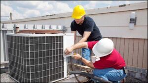 Two HVAC technicians repairing a commercial rooftop AC unit for One Way Heating And Cooling, LLC in Horizon City, TX.