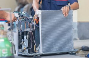 HVAC technicians repairing an open unit, exposing coils and compressor, for Ault's Cooling HVAC Services LLC in Chandler, AZ.