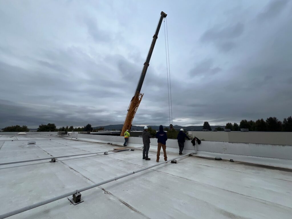HVAC technicians installing a rooftop unit with a crane for Comfort Heating, Cooling & Electrical in Post Falls, ID