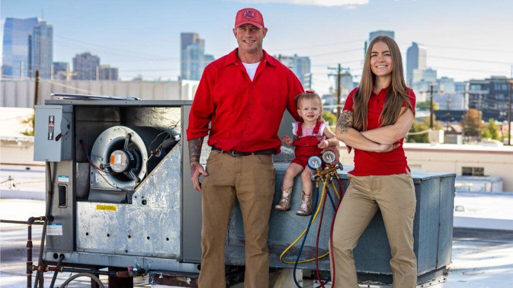 HVAC technicians standing next to an open commercial rooftop unit, ready for service by Jump HVAC in Lakewood, CO.