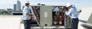 Two HVAC technicians performing repair or installation on a large commercial rooftop unit for Breeze Heating & Cooling Nashville in Nolensville, TN.