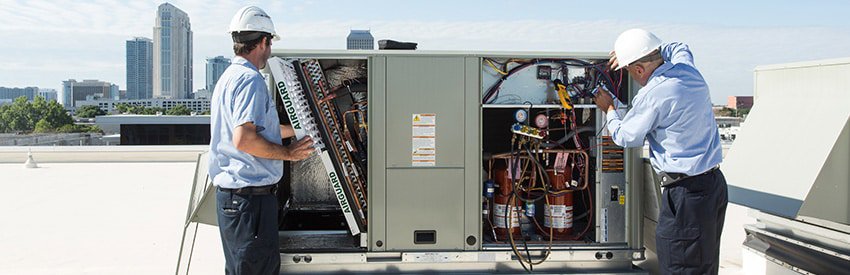Two HVAC technicians performing repair or installation on a large commercial rooftop unit for Breeze Heating & Cooling Nashville in Nolensville, TN.