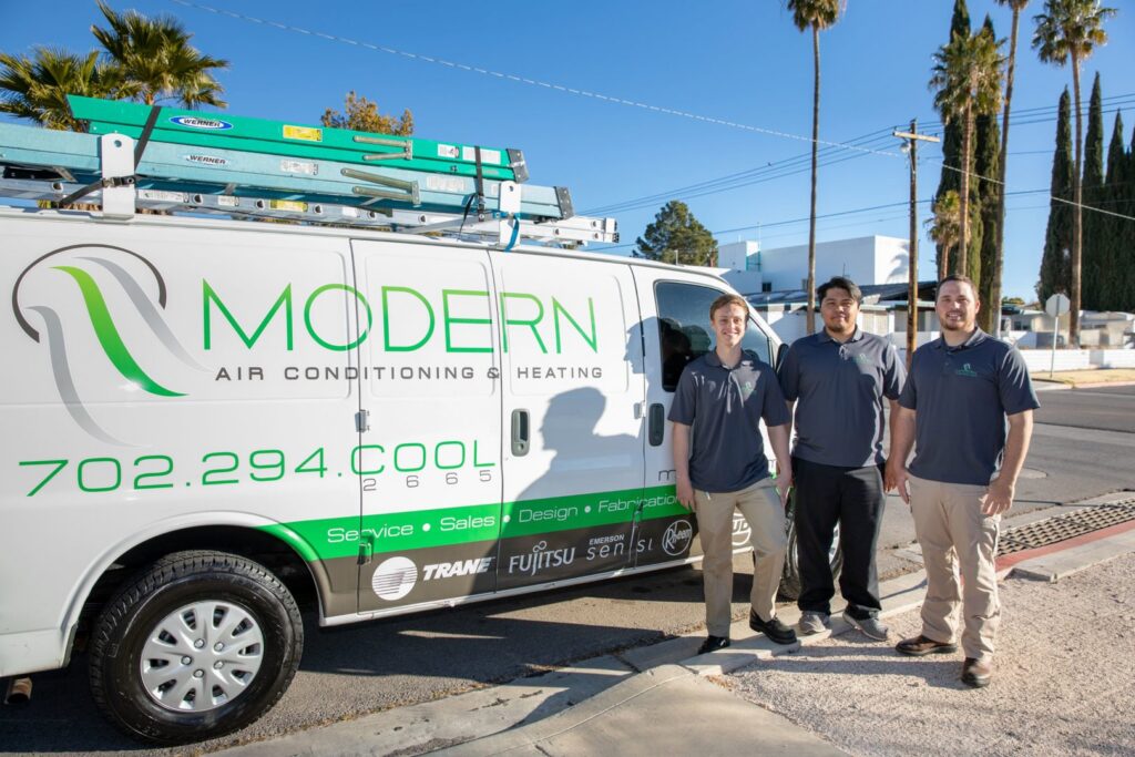 Three HVAC technicians standing proudly in front of a Modern Air Conditioning & Heating service van in Boulder City, NV.
