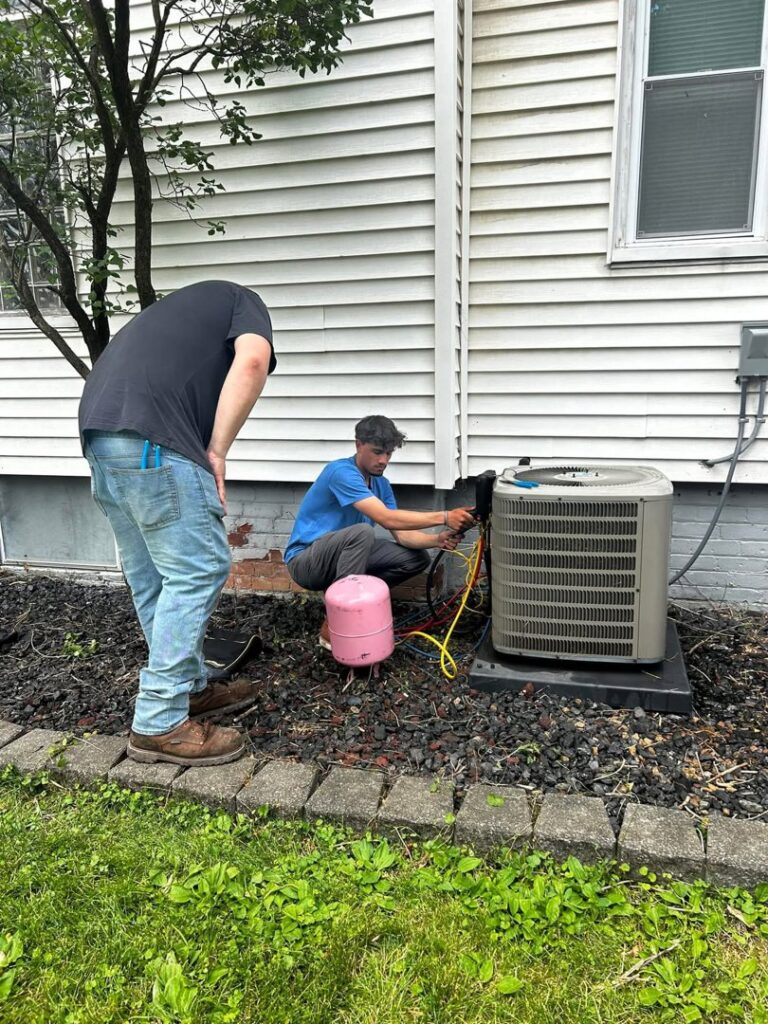 HVAC technicians servicing an outdoor air conditioning unit for Detroit Metro Mechanical, Inc. in Harrison Township, MI.