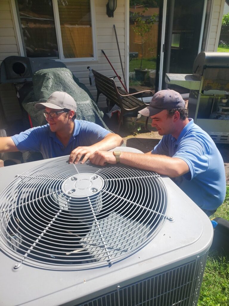 Two HVAC technicians servicing an outdoor air conditioning unit for Platinum Quality Air 500 in Hampton, VA.