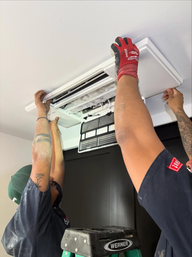 HVAC technicians performing service or installation on a ceiling-mounted unit for Royal Heating & Air LLC in Sparks, NV