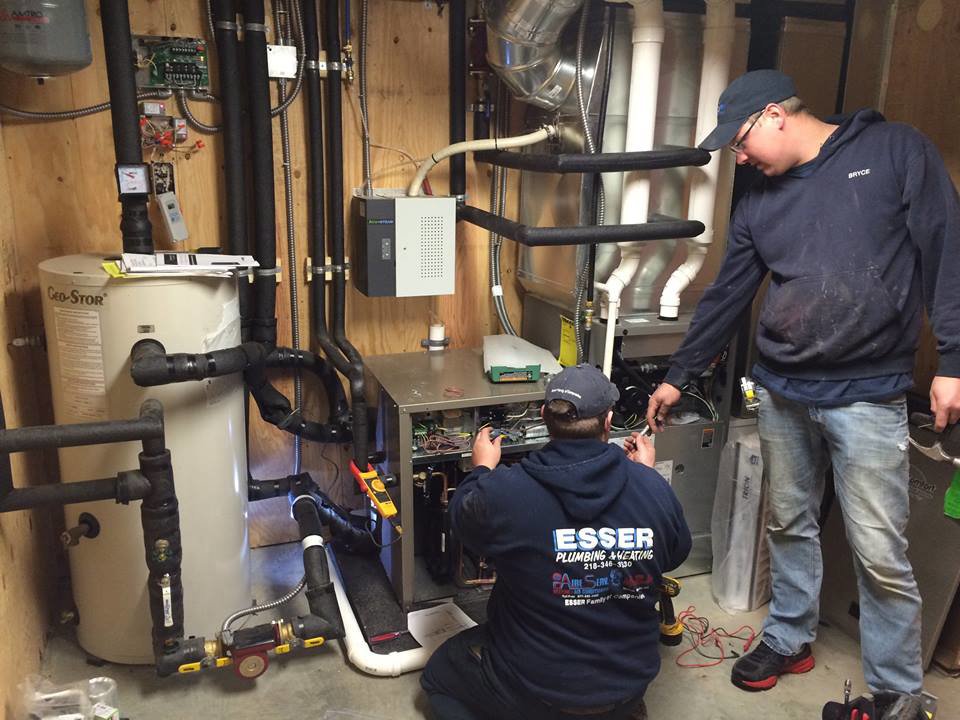 HVAC technicians servicing a furnace and boiler system in a home by Aire Serv of Fargo, ND.