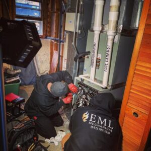 EML Mechanical technicians servicing a furnace or boiler unit in a utility room in Boston, MA.