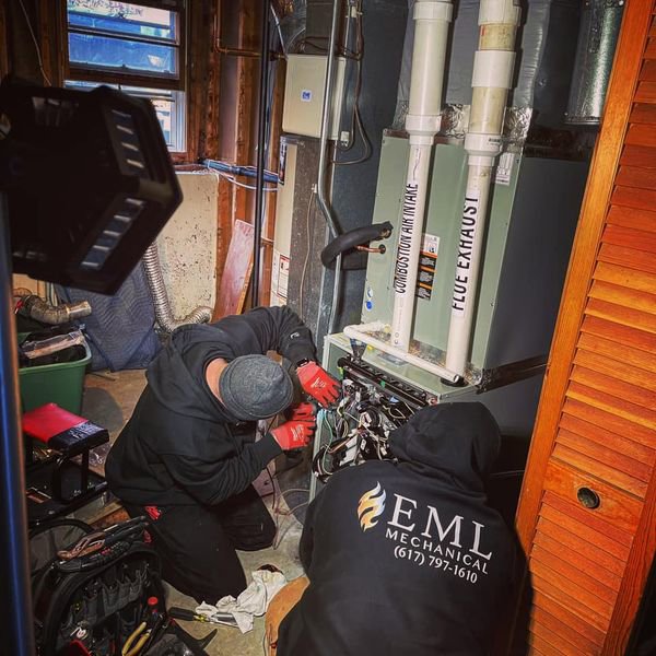 EML Mechanical technicians servicing a furnace or boiler unit in a utility room in Boston, MA.
