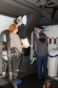 Two HVAC technicians servicing a furnace and humidifier system for Warren Mechanical, LLC in Carmel, IN.