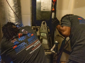 Two HVAC technicians from Cool Guys Heating & Air LLC servicing an indoor air handler unit in North Little Rock, AR.