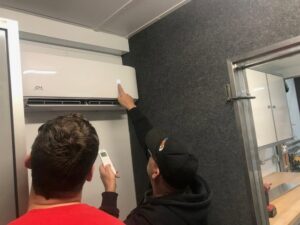 HVAC technicians servicing a mini-split unit, adjusting settings for Central Heating & Air in Sioux Falls, SD