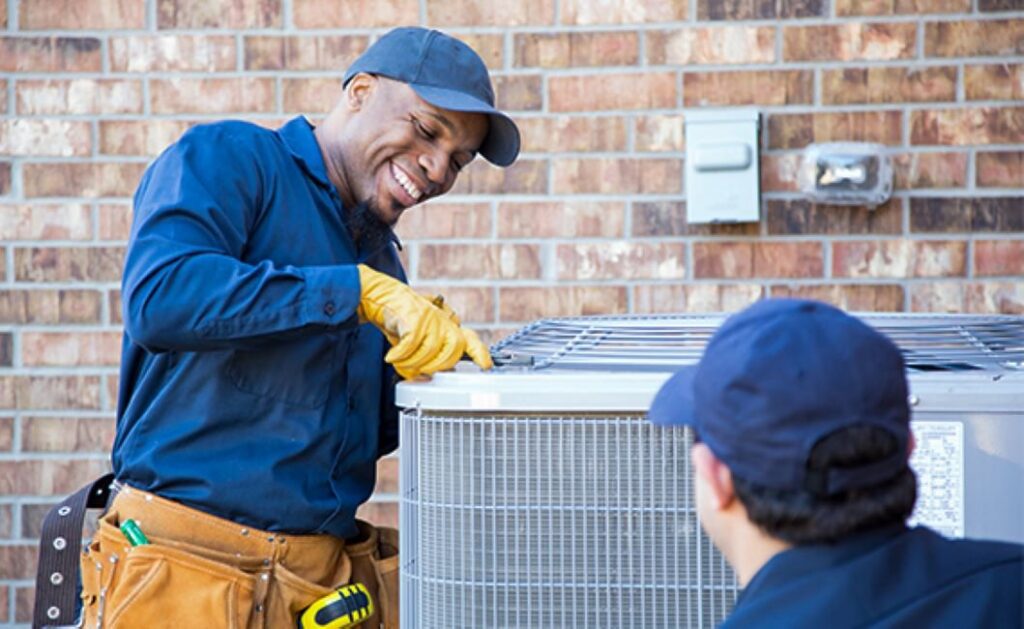 Two HVAC technicians servicing an outdoor air conditioning unit for J & J Heating and Cooling, Inc. in Lancaster, PA.
