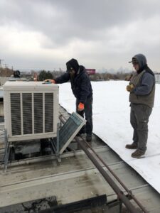 Two HVAC technicians servicing a commercial rooftop unit for 5280 Cooling Heating & Refrigeration in Lakewood, CO