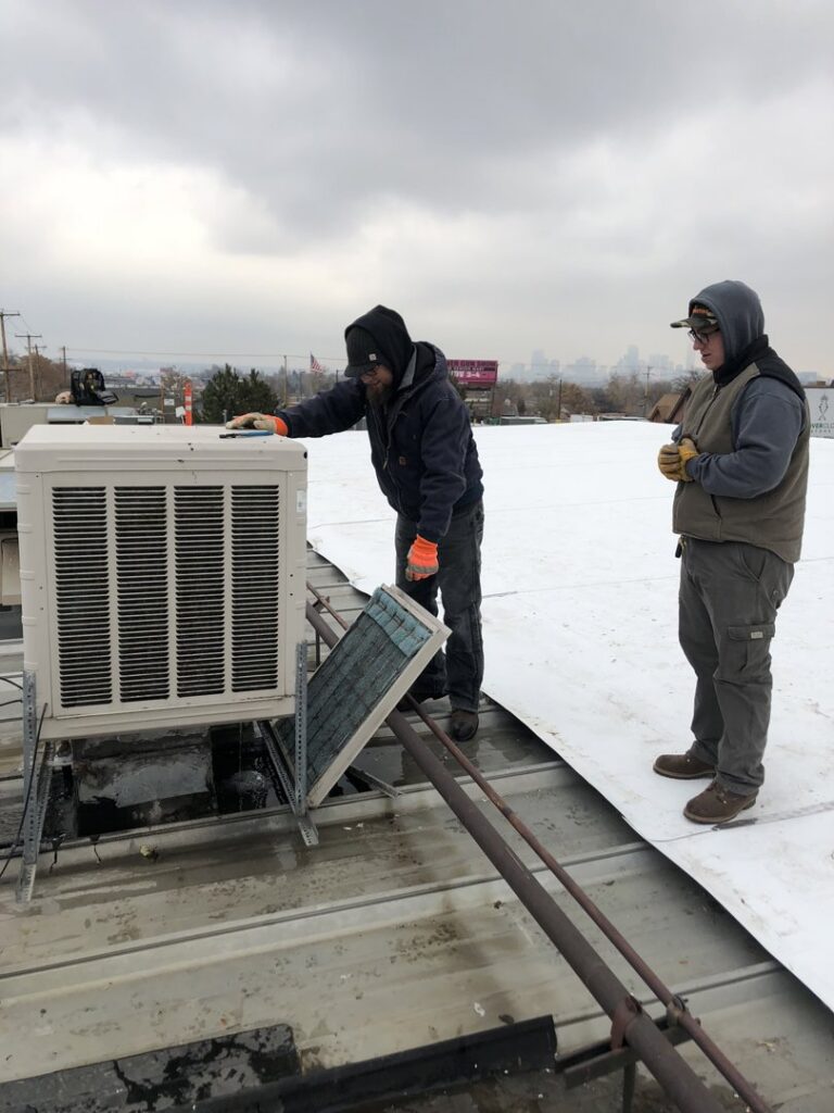 Two HVAC technicians servicing a commercial rooftop unit for 5280 Cooling Heating & Refrigeration in Lakewood, CO