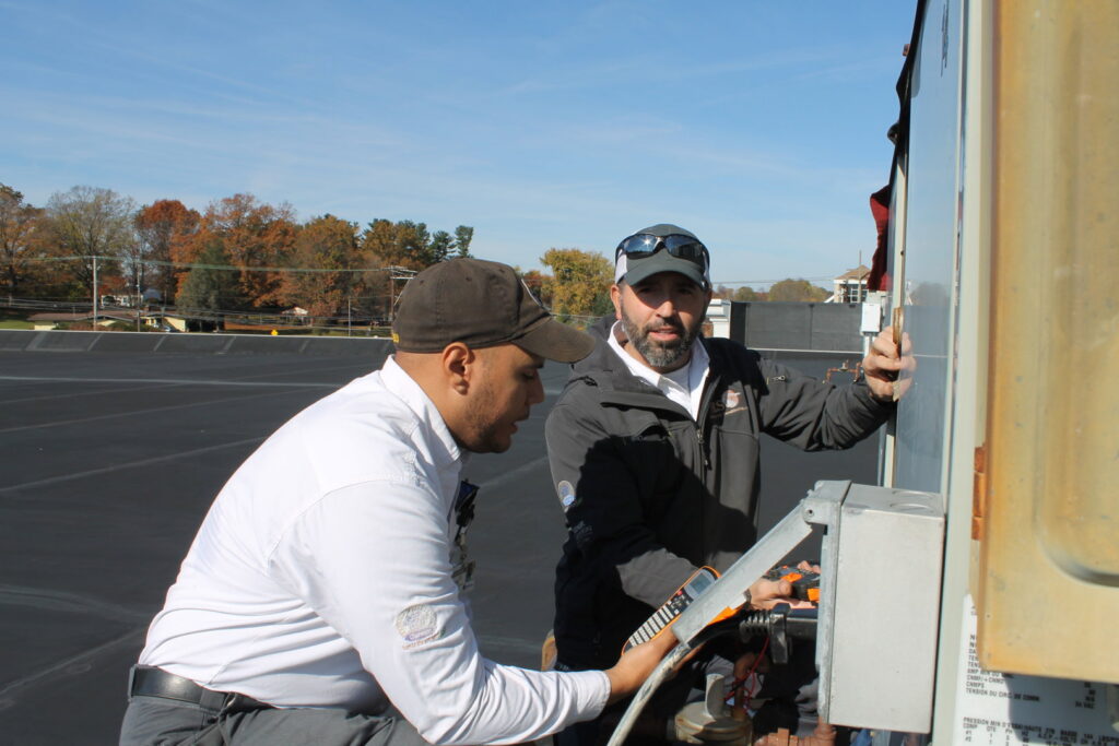 Two HVAC technicians servicing a commercial rooftop unit for RSC Heating and Air Conditioning in Lancaster, PA.