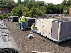 HVAC technicians servicing multiple commercial rooftop units for Benck Mechanical Inc in Somerset, WI.