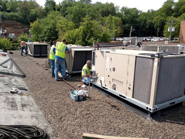 HVAC technicians servicing multiple commercial rooftop units for Benck Mechanical Inc in Somerset, WI.