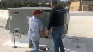 Two Lincoln Air & Plumbing technicians servicing a large Trane rooftop HVAC unit in Phoenix, AZ
