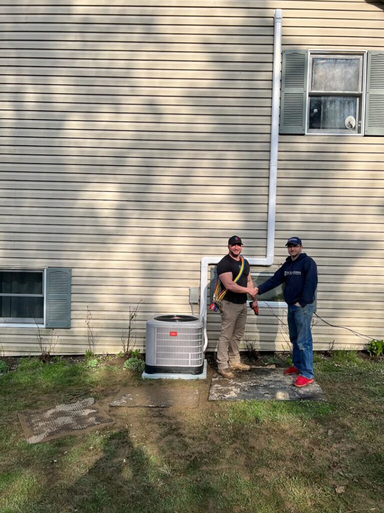 Two T. D'Albora Heating and Cooling technicians shaking hands after completing an AC service in Erie, PA.