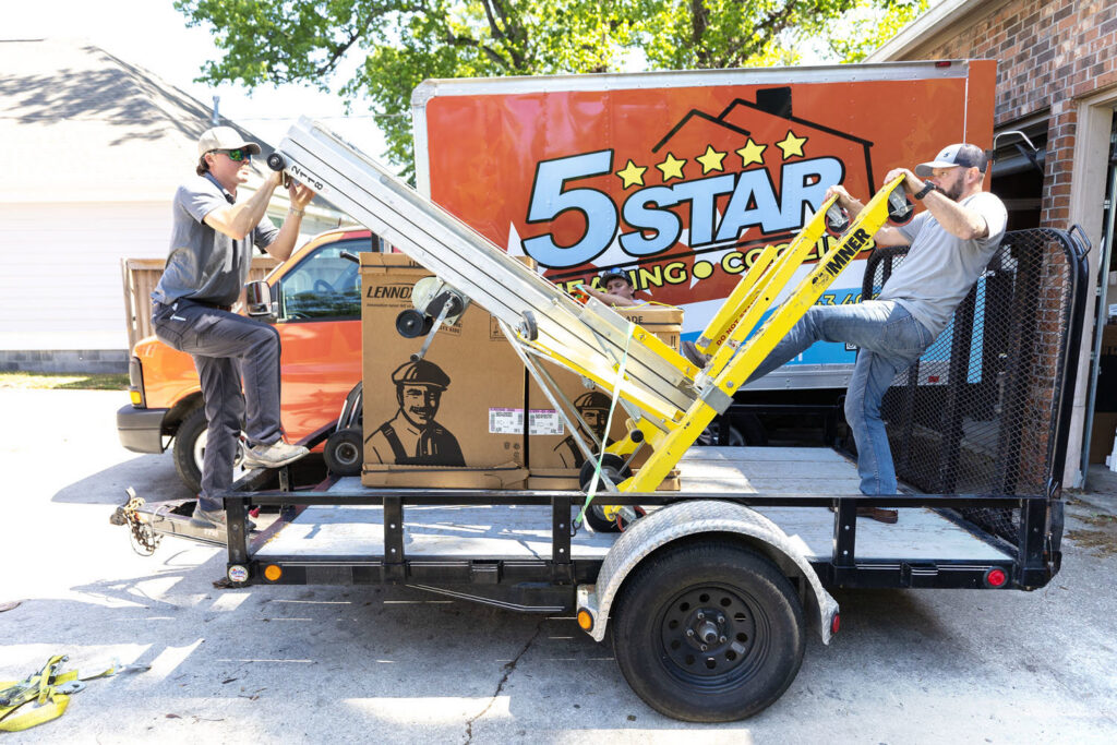 HVAC technicians unloading new heating and air conditioning equipment from a trailer for 5 Star Charleston Heating and Air in Charleston, SC.