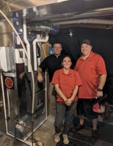 Three HVAC technicians proudly standing by a new furnace installation completed by 72 Degrees in Ankeny, IA.