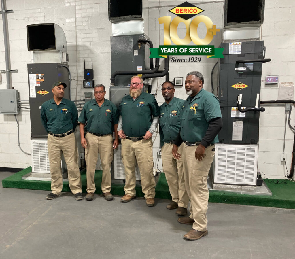 A team of Berico HVAC technicians standing in front of multiple indoor furnace and air handler units in Greensboro, NC