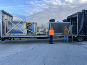 HBC HVAC technicians standing with a new delivery of heating and cooling equipment on a trailer in Cranston, RI.