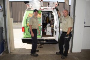 Two HVAC technicians from Nortek Environmental, Inc. standing by their service van filled with tools in Naperville, IL.
