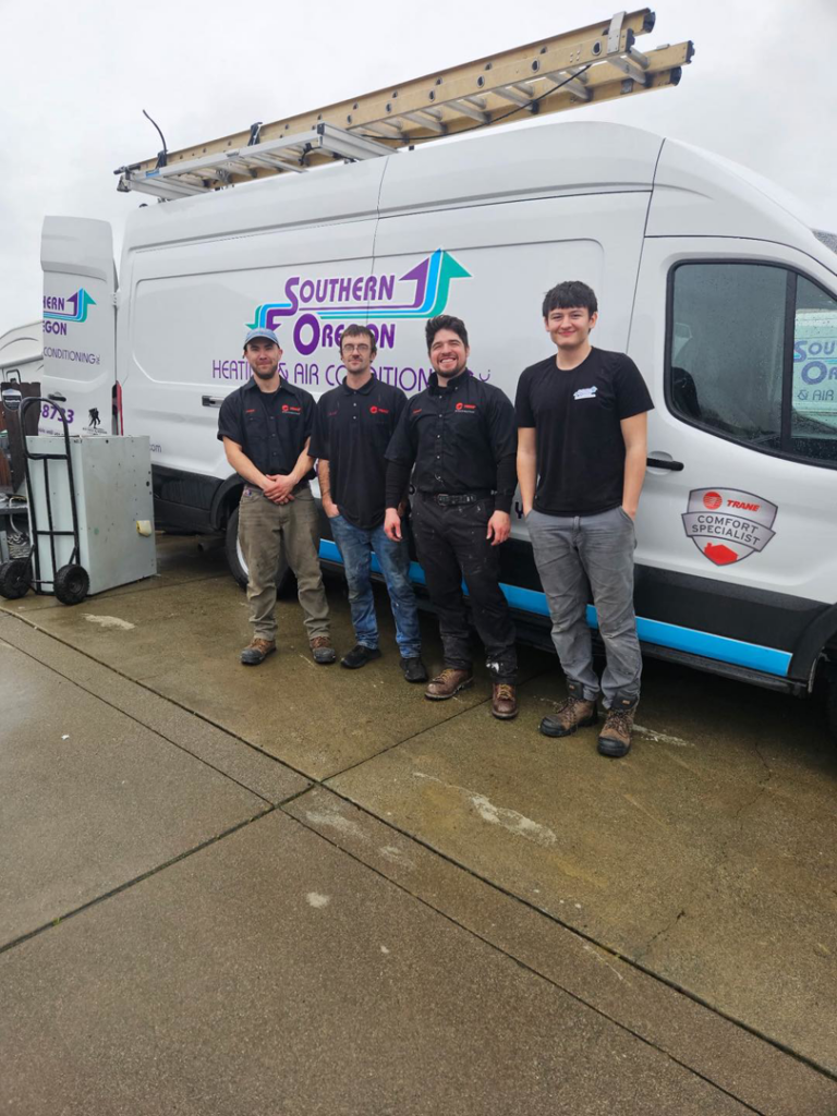 Four HVAC technicians standing with a branded service van from Southern Oregon Heating & Air Conditioning in Medford, OR