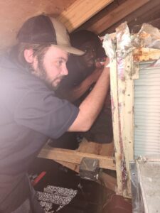 Two HVAC technicians working on an air conditioning unit in a cramped attic space for Sterling Service of Florida Inc in Tallahassee, FL.