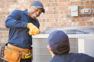 Two HVAC technicians working together on an outdoor AC unit for Southside Energy in Chesapeake, VA.
