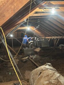 Two HVAC technicians working on an air handling unit in a residential attic for Dewees HVAC in Conway, AR.