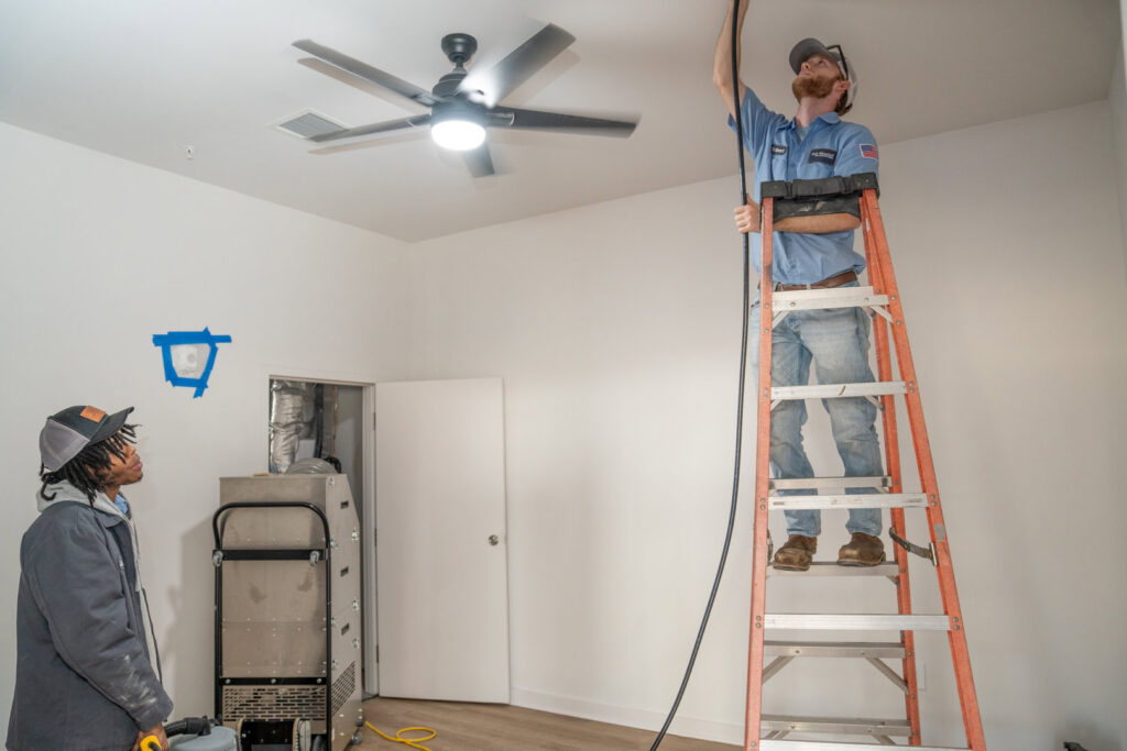 HVAC technicians from Bob Woodall Air Care Systems working on ceiling ductwork and air quality equipment in Dothan, AL.
