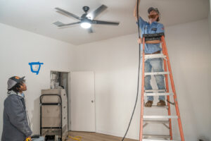 HVAC technicians from Bob Woodall Air Care Systems working on ceiling ductwork and air quality equipment in Dothan, AL.