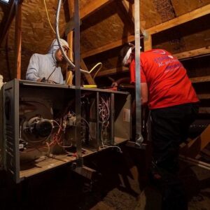 Two HVAC technicians working on a furnace or air handler in an attic for Diamond AC and Heating in Phoenix, AZ.