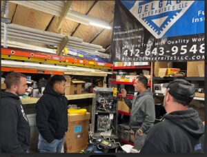 HVAC technicians from Delgado Enterprises inspecting an open furnace unit during a job in Pittsburgh, PA